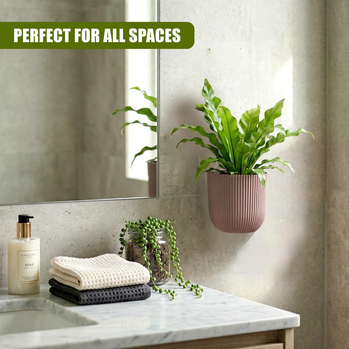 A bathroom counter with soap dispenser and towels, featuring two decorative wall planters with green foliage.