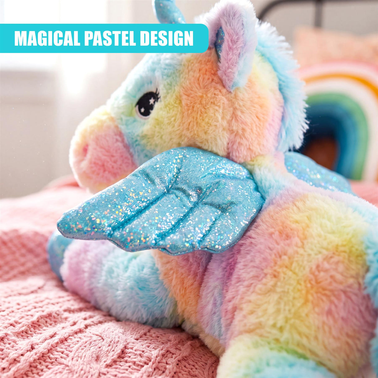 Colorful plush unicorn toy rests on pink blanket with rainbow decor.