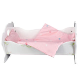 A white wooden doll cradle is shown with pink patterned bedding, pillows, and a sheet.