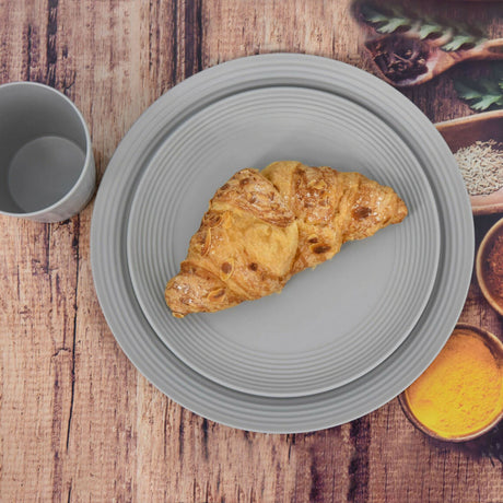 A grey croissant on a plate next to spices.