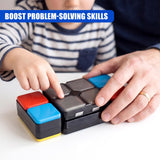 Two people work together manipulating a multi-colored, segmented puzzle cube game on a surface.