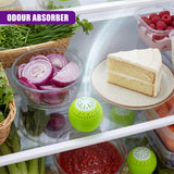 Three perforated green deodoriser balls are displayed among various fresh refrigerated foods.