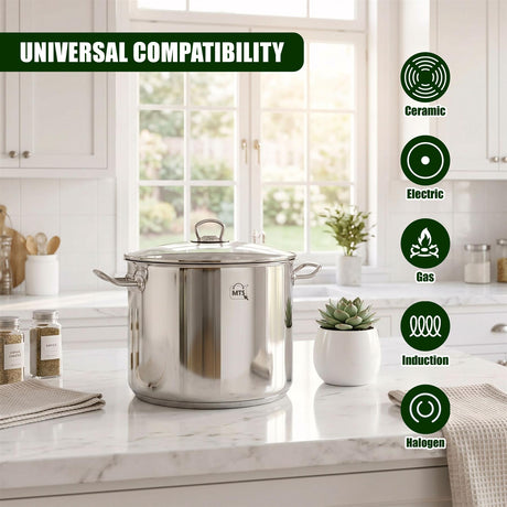 A large, polished stainless steel stock pot with a clear glass lid rests on a light marble countertop.