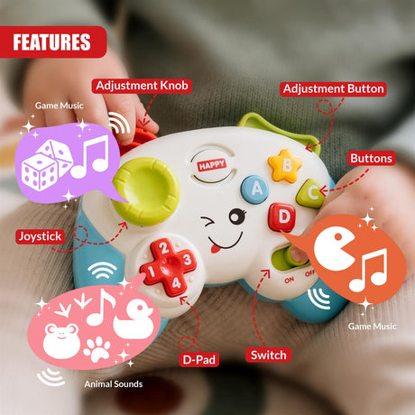 A baby's hands hold a white game controller toy with green and blue accents, featuring labelled buttons and joysticks for
