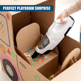 A white toy vacuum cleaner rests inside an open, decorated cardboard box with scattered colorful pieces.