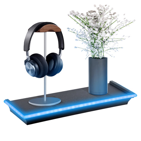 Black floating shelf with blue LED lights holding a headphone stand and vase of white flowers