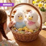Two plush chick toys rest in a woven basket filled with pastel painted eggs and daffodils.