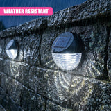 Circular black solar pathway lights are mounted into a wet stone wall, featuring illuminated LED panels.