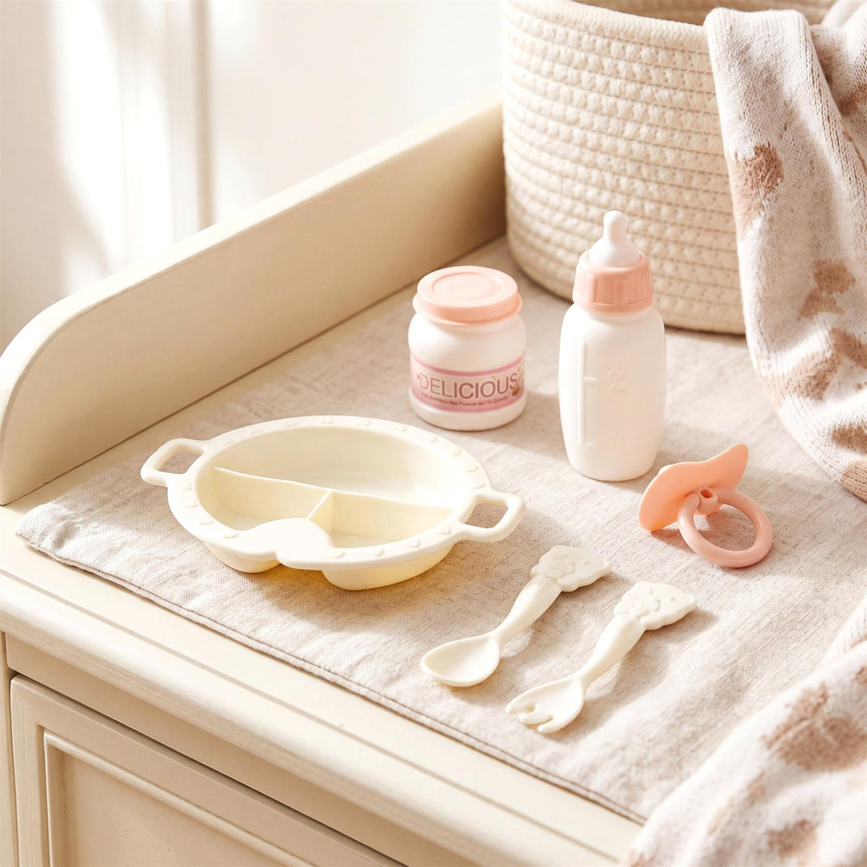 Shallow feeding tray, baby jar, bottle, spoons, and teether accessory displayed on a white surface.