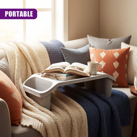 Tray table in front of couch, cozy blankets, books and coffee cup, two cushions, soft ambient lighting.

[alt: "Couch with bed tray table and storage for living room. Wooden top over white frame, functional coffee table. Comfortable blanket, pillow, books on tabletop." - UKBuyZone