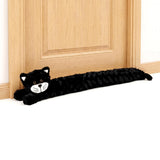 Black cat-shaped fabric draught excluder lying along the base of a light wooden door.