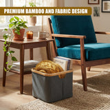 A gray fabric hamper stands on a rug, filled with yellow folded laundry and several books.