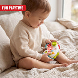 A baby wearing a beige knitted sweater sits on a bed playing with a Game Controller Toy by The Magic Toy Shop