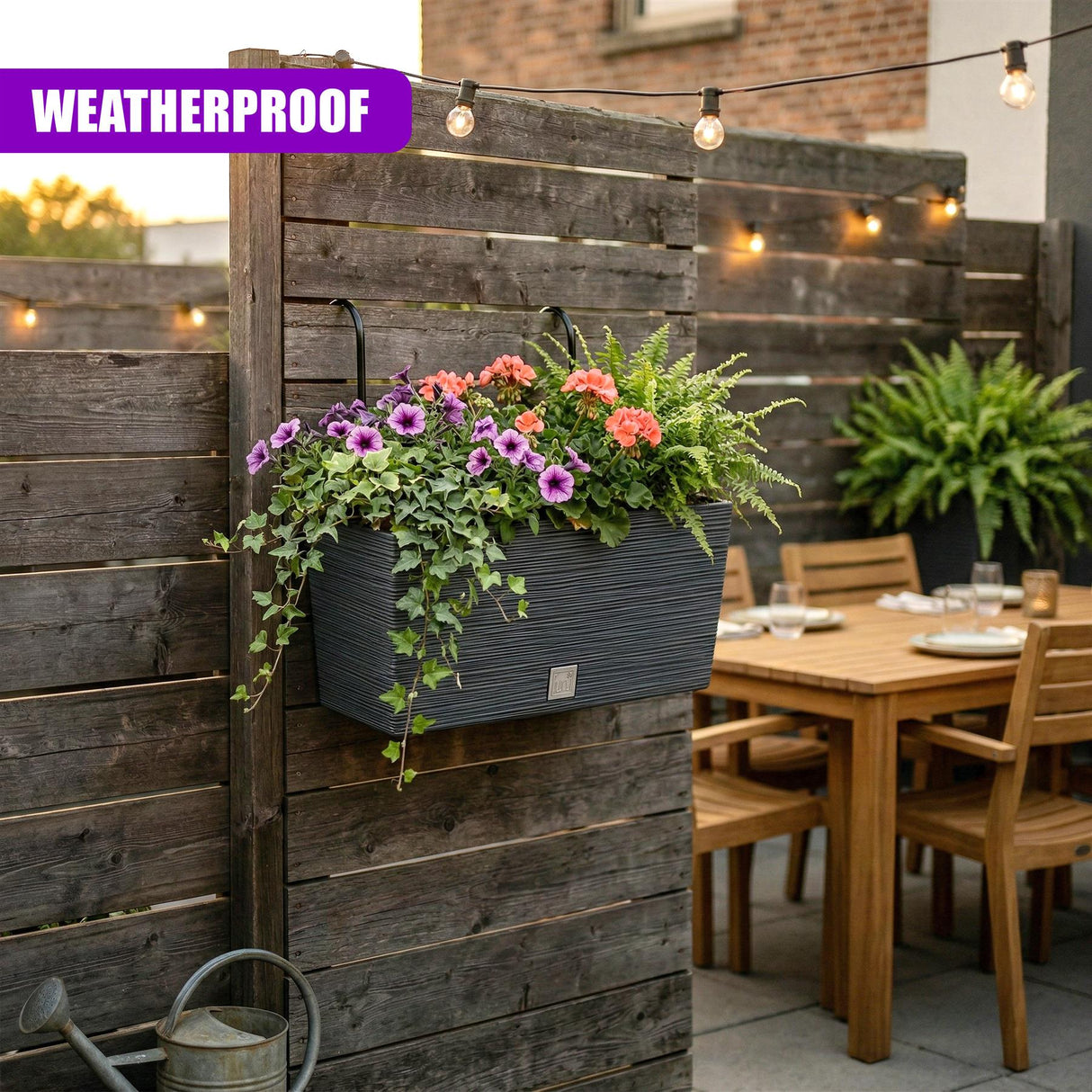 A gray, horizontal planter containing various colorful flowering plants, mounted on wood slats.