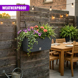A gray, horizontal planter containing various colorful flowering plants, mounted on wood slats.