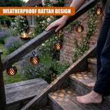 Patterned rattan solar lights strung along a dark wooden outdoor staircase railing.