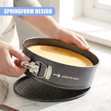 Hands hold a round springform cake pan with a locking release and fitted base.