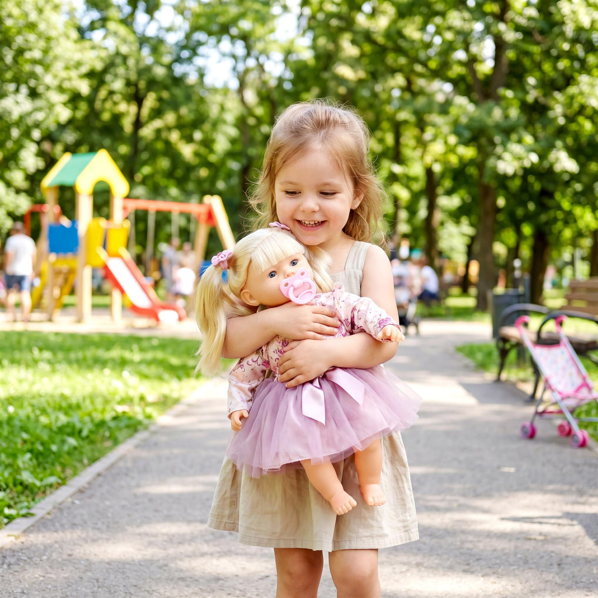 A young girl smiles while holding a blonde doll dressed in a pink and white outfit.