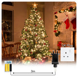 A beautifully decorated Christmas tree adorned with lights, baubles, and a star on top, set in a cozy living room with stockings hanging on the fireplace. The image features a 3-meter battery adaptor with a UK plug, designed for powering decorations and electronic devices. Ideal for festive lighting and seasonal decorations. Available at ukbuyzone.