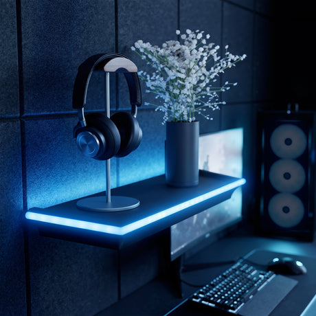 Black floating shelf with blue LED lights holding headphones and a vase of flowers