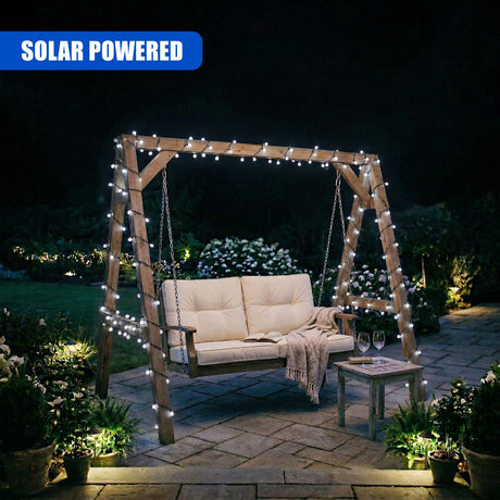 Outdoor wooden swing arch draped with lights, featuring a cushioned bench and accompanying small patio table.