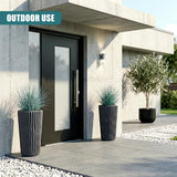 Pair of tall, ribbed anthracite planters holding greenery, placed outside a modern concrete entrance.