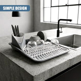 White dish drying rack holding glassware and utensils arranged on a countertop.