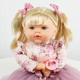 This is a doll from the brand Bibi. The doll has long hair and is wearing a dress with pink flowers. It's also holding a baby doll in its arms.