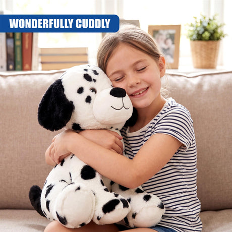 A young girl smiles while hugging a plush Dalmatian stuffed toy on a sofa.
