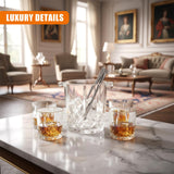 Glass containers holding amber liquid and an ice bucket filled with ice rest on a marble surface.