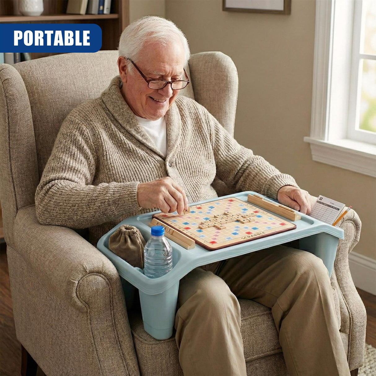 A man sitting in a chair and playing a board game, holding a tray table with storage underneath. He's wearing glasses and has gray hair. On his lap sits a game of dominoes. - UKBuyZone