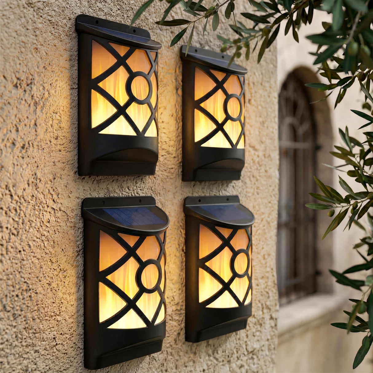 Four lit outdoor wall sconces with patterned panels mounted on a textured wall surface.