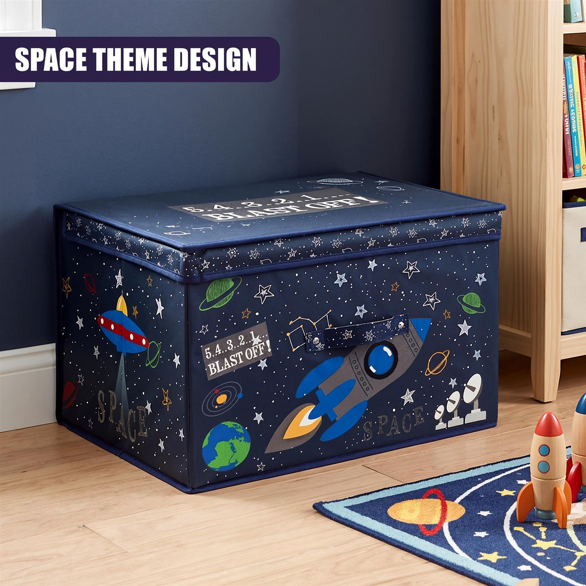 A large blue storage box with a space theme design featuring stars, planets, rockets and UFOs, placed on a wooden floor next