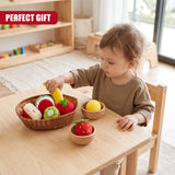 A toddler in a brown top plays with a fabric fruit basket set on a wooden table