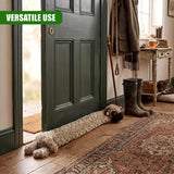 A plush dog figure is placed on a patterned rug at the base of a dark green door.