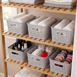 Six gray woven storage baskets organized on wooden shelves holding folded linens and toiletries.