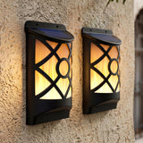 Two rectangular black outdoor sconces with decorative paneled glass are mounted on a textured stucco wall.