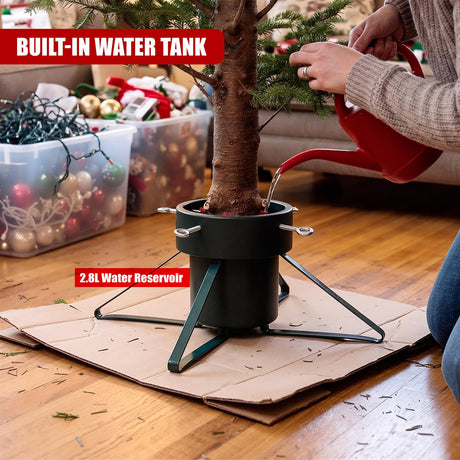 A person pours water from a red watering can into a black metal Christmas tree stand with a built-in 2.8L water reservoir