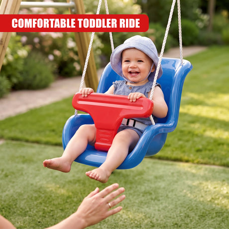 A smiling baby wearing a blue hat and denim outfit sits securely in a red and blue toddler swing seat suspended by ropes in