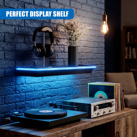Black floating shelf with blue LED lights holding headphones and a vase against a brick wall