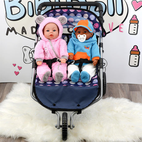 Two dolls dressed in pink and blue sit in a dark stroller on a fluffy white surface.