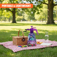 A basket, purple water sprayer, and colorful sponge balls sit on a red and white picnic blanket outdoors.