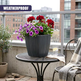Large black ribbed planter holding colorful flowers on a small outdoor bistro table.