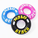 Three inflatable ring toys in blue, pink, and black are printed with the words "NALU BEACH."