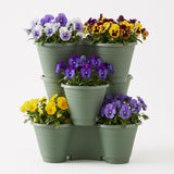 Three stacked green planters display vibrant arrangements of mixed yellow and purple flowers.