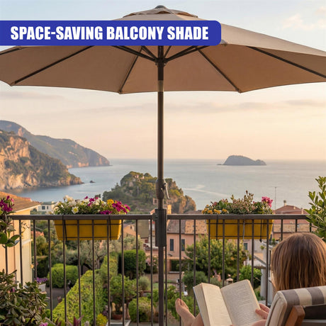 A person reads on a balcony beneath a parasol, viewing the distant ocean and coastline.