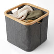 Rectangular gray hamper with a wooden frame, currently holding folded textiles and laundry items.