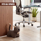 A woven kitten door stopper rests against a wood paneling wall in an office workspace.