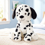 Black and white Dalmatian stuffed dog toy sitting on a cream-colored textured fabric.