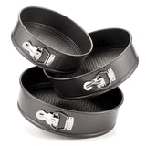 Three sized black springform baking tins are stacked on a white background.